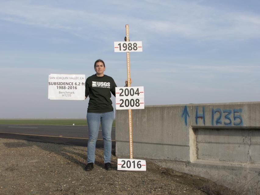 Image shows A USGS staff member marks the progression of land subsidence due to groundwater pumping along Highway 152 in Merced County. 