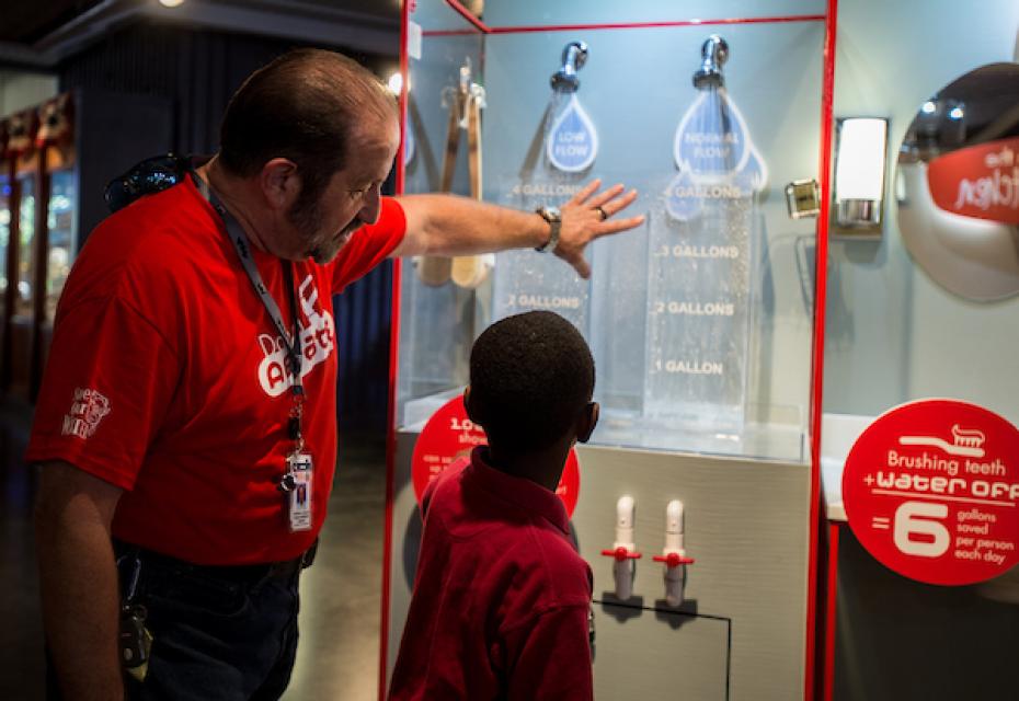California Department of Water Resources employee Michael Miller explains low-flow shower heads to a young fair-goer as part of an indoor exhibit at the California State Fair in 2014. 