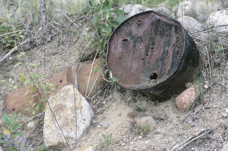 barrel half-buried in the ground, posing a threat to groundwater.