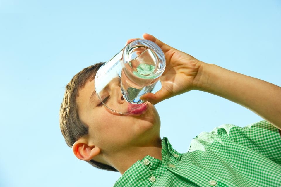 Child drinking a glass of water.