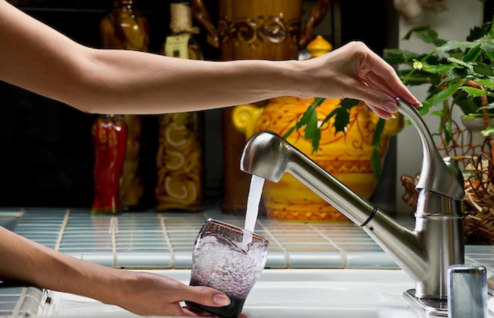 Filling a glass with clean water from the kitchen tap.