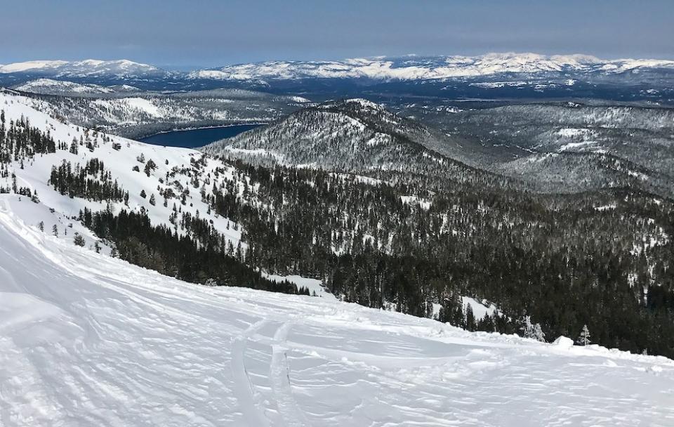 Picture shows the snowy Sierra Nevada from atop a ridge looking out at distant slopes.