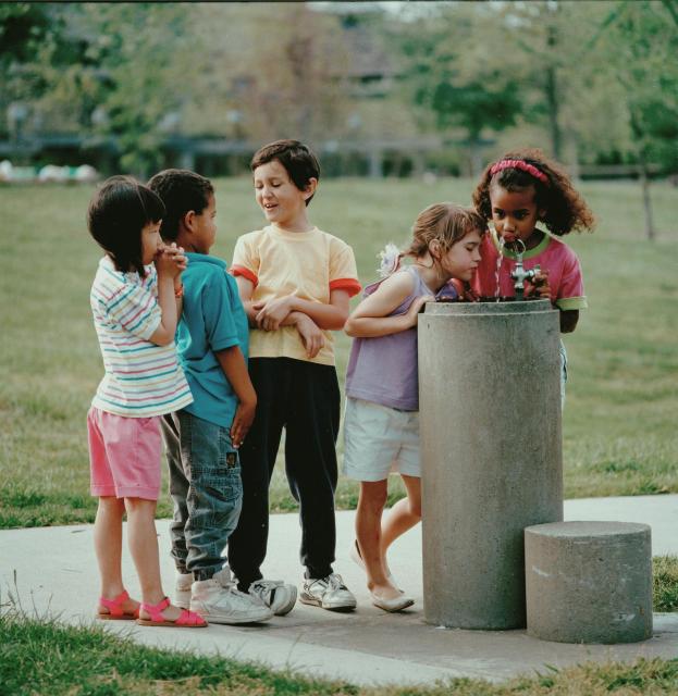Children clustered around a drinking fountain.