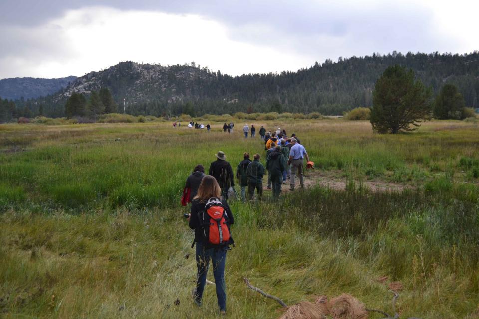 Headwaters Tour participants hike through a meadow to examine water resources.