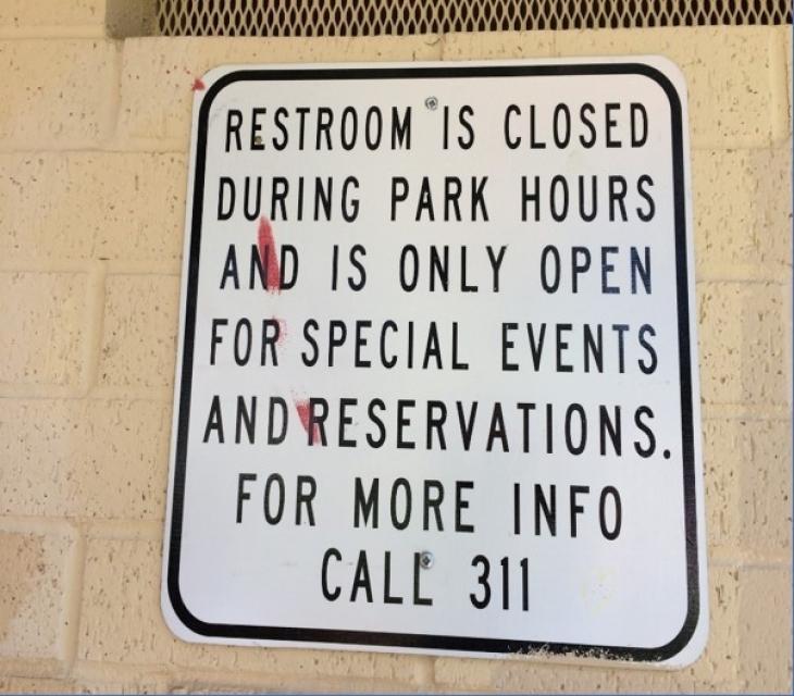 Sign on a public restroom in a Sacramento city park explains the restroom is closed during park hours and is only open for special events and reservations.
