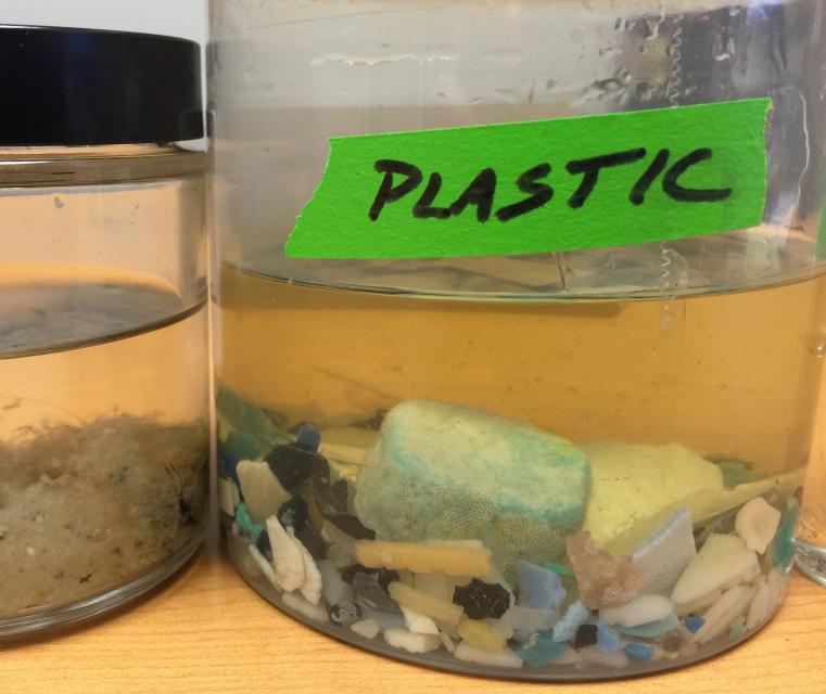 Image shows microplastic debris in a jar of water.