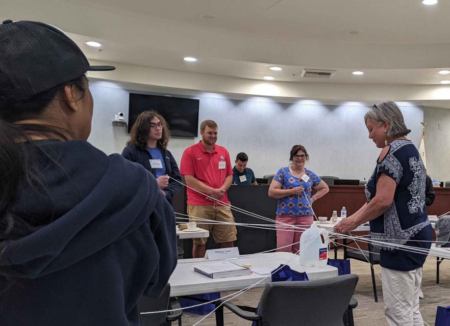 Photo shows teachers trying their hand at a classroom lesson on water.