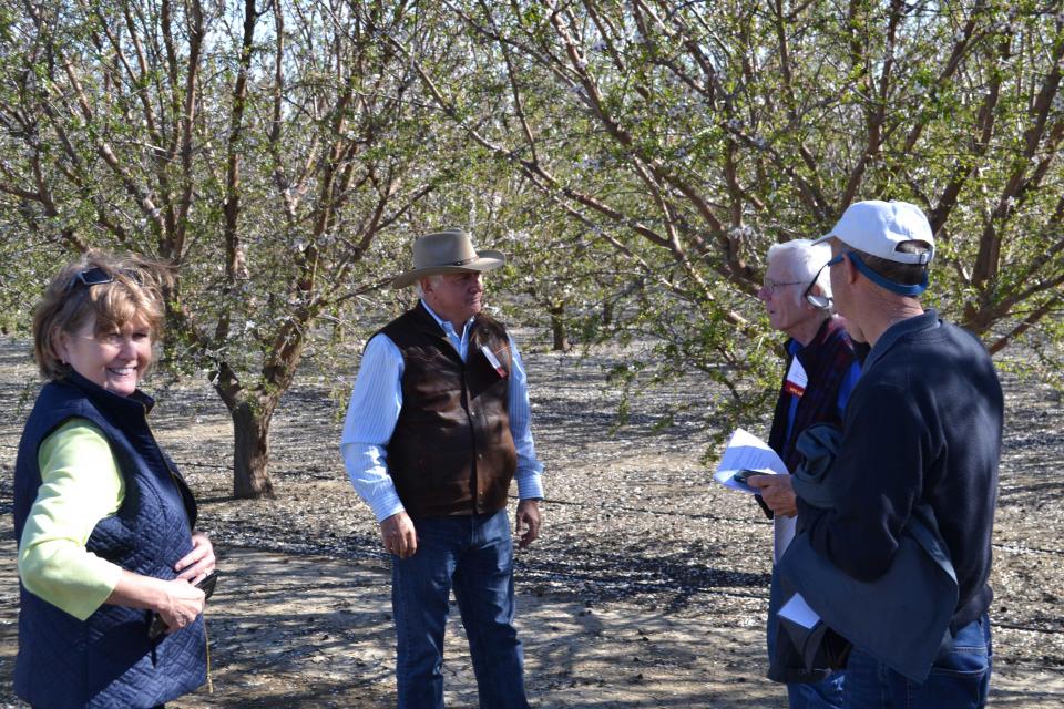 Farmer Joe Del Bosque talks with Central Valley Tour participants during a stop at his orchard. 